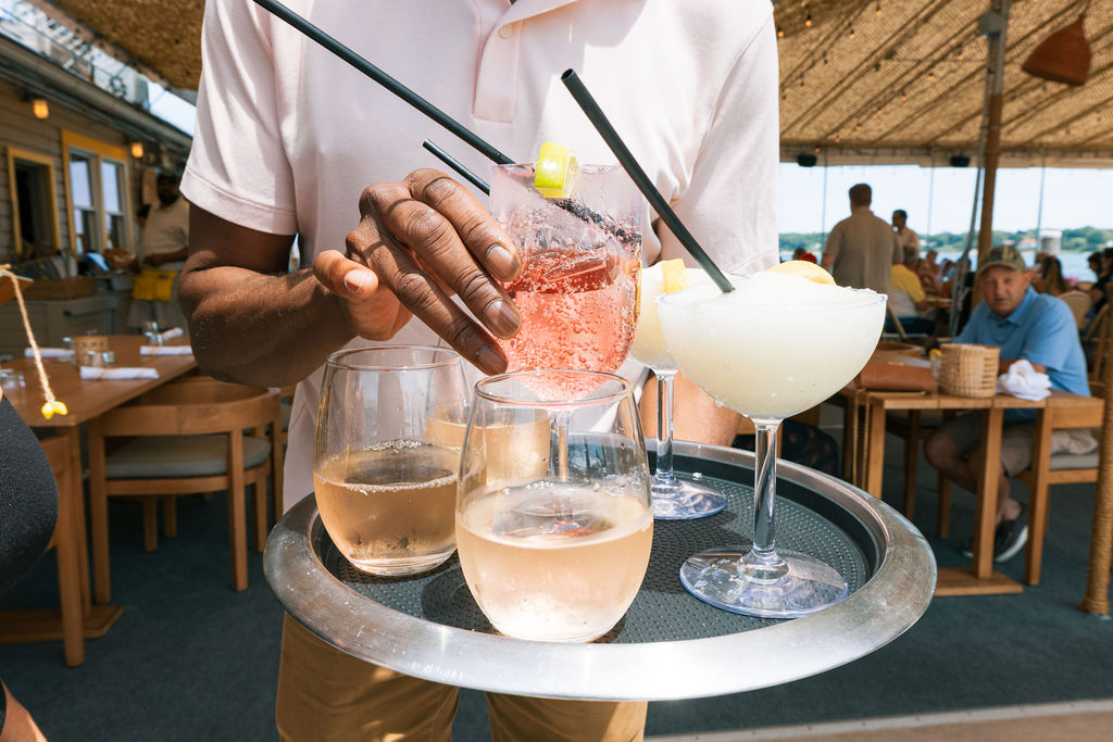 Server delivering frozen cocktails and rosé on a tray