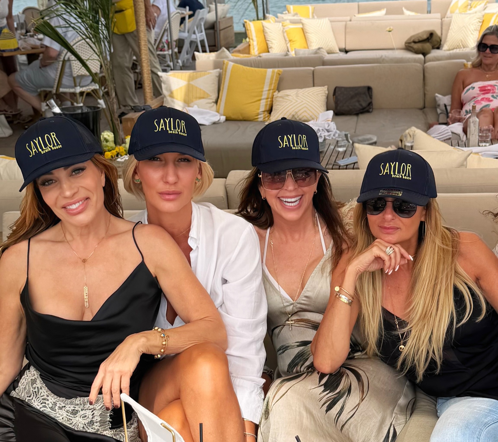 Friends in Saylor Beach House caps lounging dockside